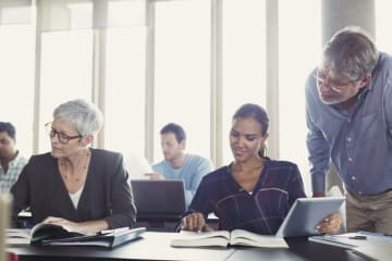 Adult learners studying with their professor in a continuing education classroom