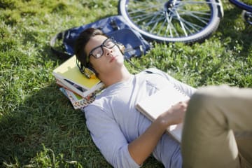 Student listening to music and relaxing on grass outside