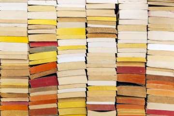 A stack of books in warm colors against a wall