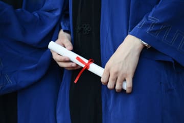 A college graduate in a gown holding a diploma