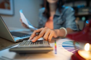 Woman typing on calculator going over finances