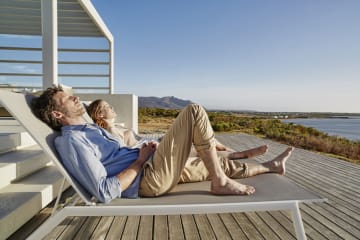 A couple outside tanning on lawn chairs