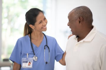 Female adult-gerontology nurse talking with male patient