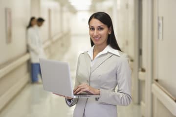 A healthcare administrator holding a laptop