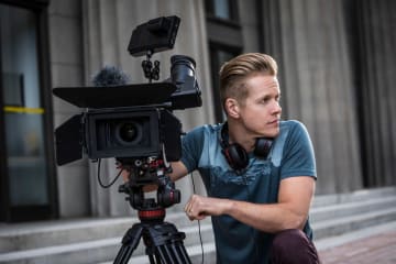 man kneeling next to a camera during filming