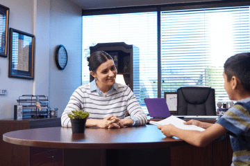 woman principal speaks with boy student