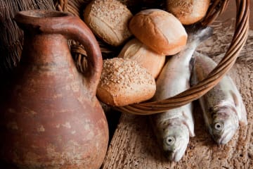 Loaves of bread and fish with old clay pitcher as a model for one of the miracles of Jesus