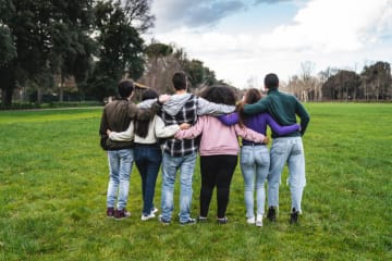 Godly friends supporting each other with interlinked arms on a grassy field