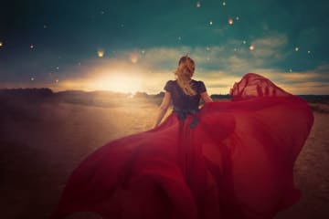 girl standing in field and dress flowing in the wind