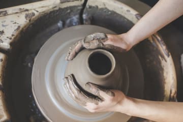 Pair of hands carefully mold a jar of clay