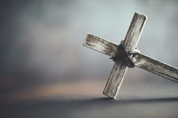 A cross lays on its side with eery smoke looming in the background