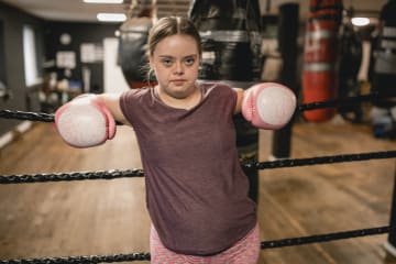 Young female boxer against the ropes fighting the good fight of faith