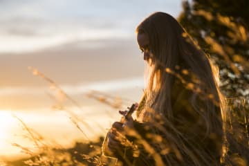 Young woman playing ukulele and worshipping in the early morning sunlight