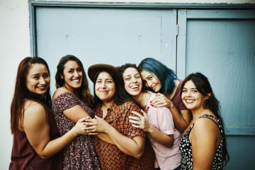 Group of multicultural women do a group photo together in front of a blue wall