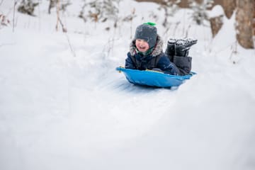 Joyful little boy sledding in the snow