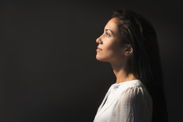 Young woman looks at the light to left with black background