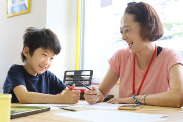 Female paraprofessional laughing and working with young student in classroom