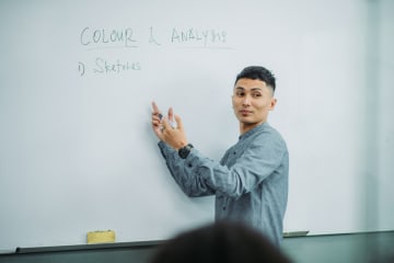 Male professor teaching students using whiteboard lesson in classroom