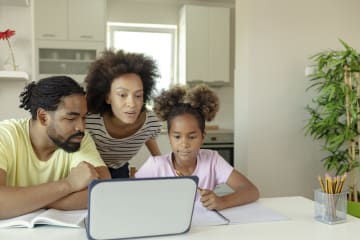parents helping young child with online education