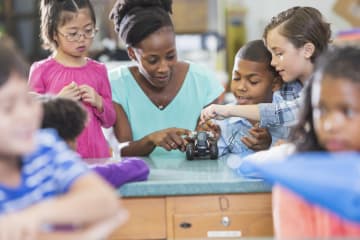 Black STEM teacher doing electricity experiment with students