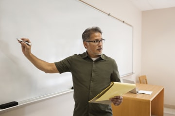 Male teacher writing on whiteboard to teach students how to learn to read