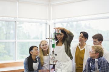 Female STEM teacher working with young students in science classroom