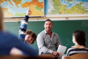 A male teacher calling on a student with his hand raised