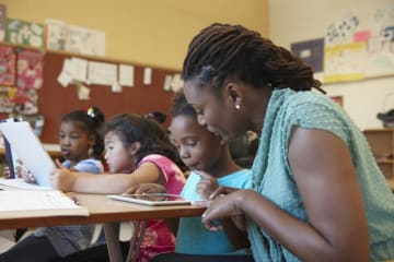 Female teacher and students in classroom doing gratitude exercises