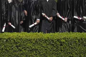 Education graduates in their gowns holding diplomas
