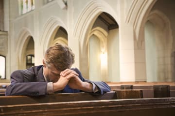 Man bows his head to pray in church for forgiveness