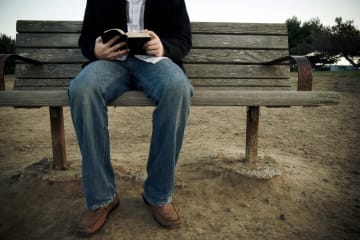 guy sitting on bench with open Bible