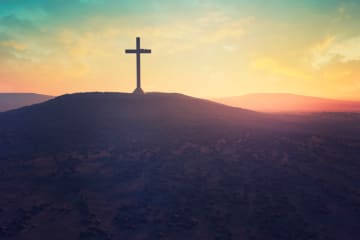 Cross on a hill in front of a sunset