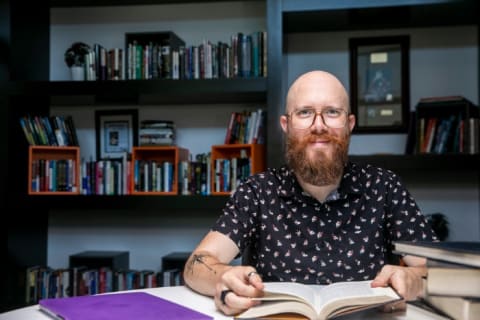 GCU history student sitting at table reading books