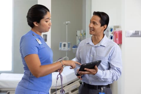 Nurse in hospital setting talking to man with tablet