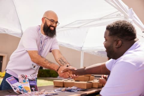 2 students shaking hands over table outside