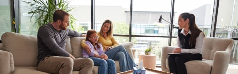 A family sitting on a couch talking to a therapist 