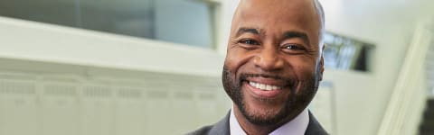 adult doctoral graduate stands in the lobby of his new job