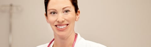 Female nurse smiling in white coat in a hospital setting