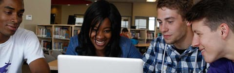 Group of four students working on computer in library