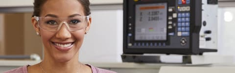 African American woman wearing safety glasses in CNC machinist lab