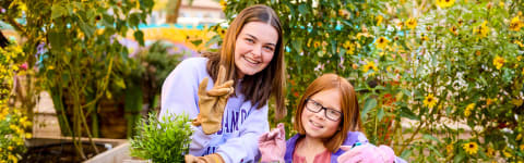 Psychology degree student working in GCU garden with young girl student