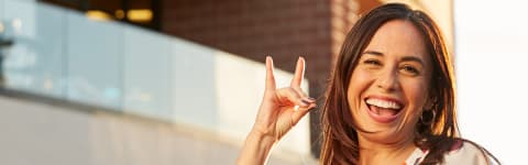 Online degree student smiling and holding Lopes Up hand sign