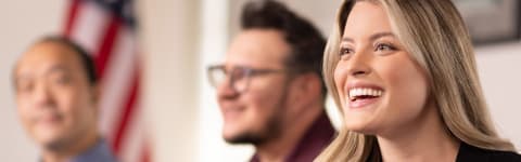 Student sitting in classroom smiling with blurred students in the background