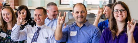 Faculty members smiling and gesturing with "lopes up" symbol