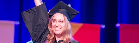 Student raising her degree at commencement ceremony for College of Theology