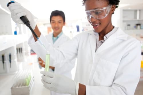 African-American female scientist putting a solution in test tube to use scientific method in a lab