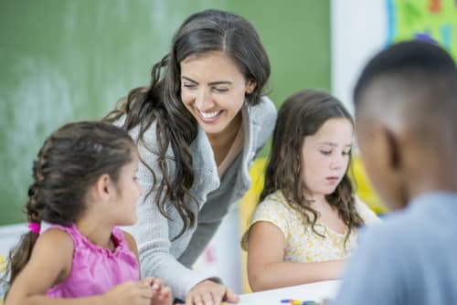 Smiling female teacher helping students