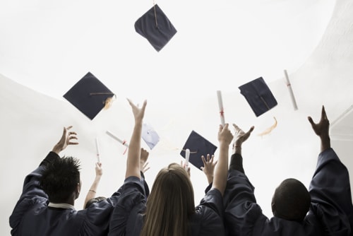 Three graduates throwing up their motarboards