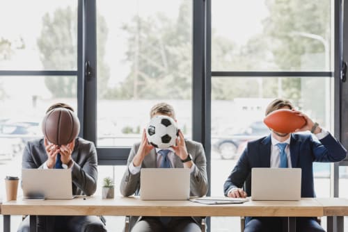 Three office workers holding different sports balls in their hands