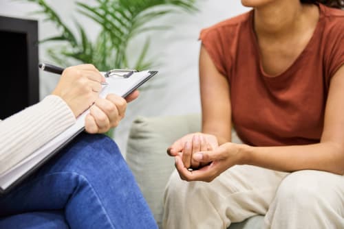 Close up of counselor writing on clipboard while with patient